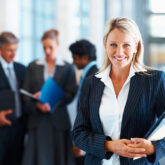 Happy businesswoman with colleagues in the background