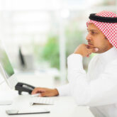 middle eastern businessman looking on a computer screen, sitting in his office