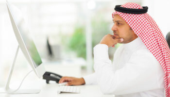 middle eastern businessman looking on a computer screen, sitting in his office